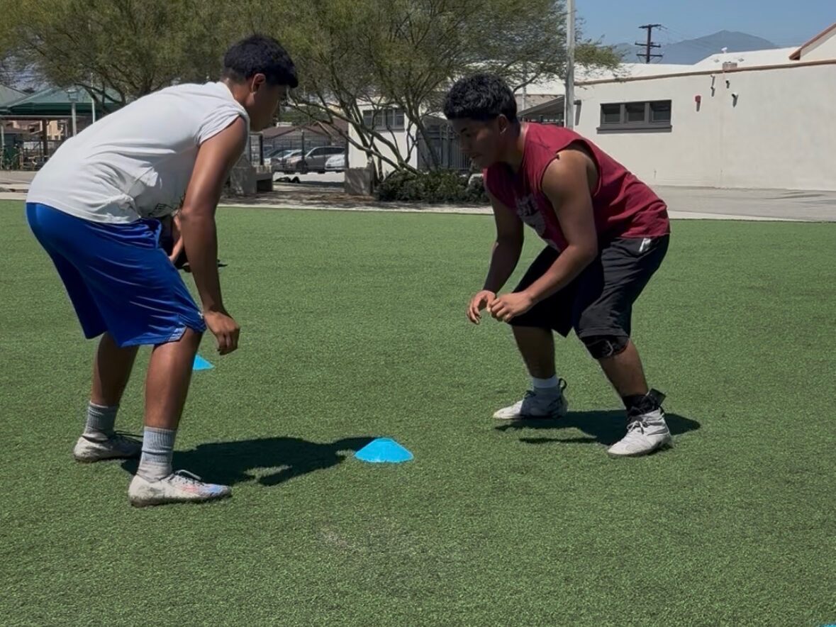 Two athletes in a stance facing each other across cones